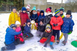 kilkanaścioro dzieci pozuje do zdjęcia z bałwanem